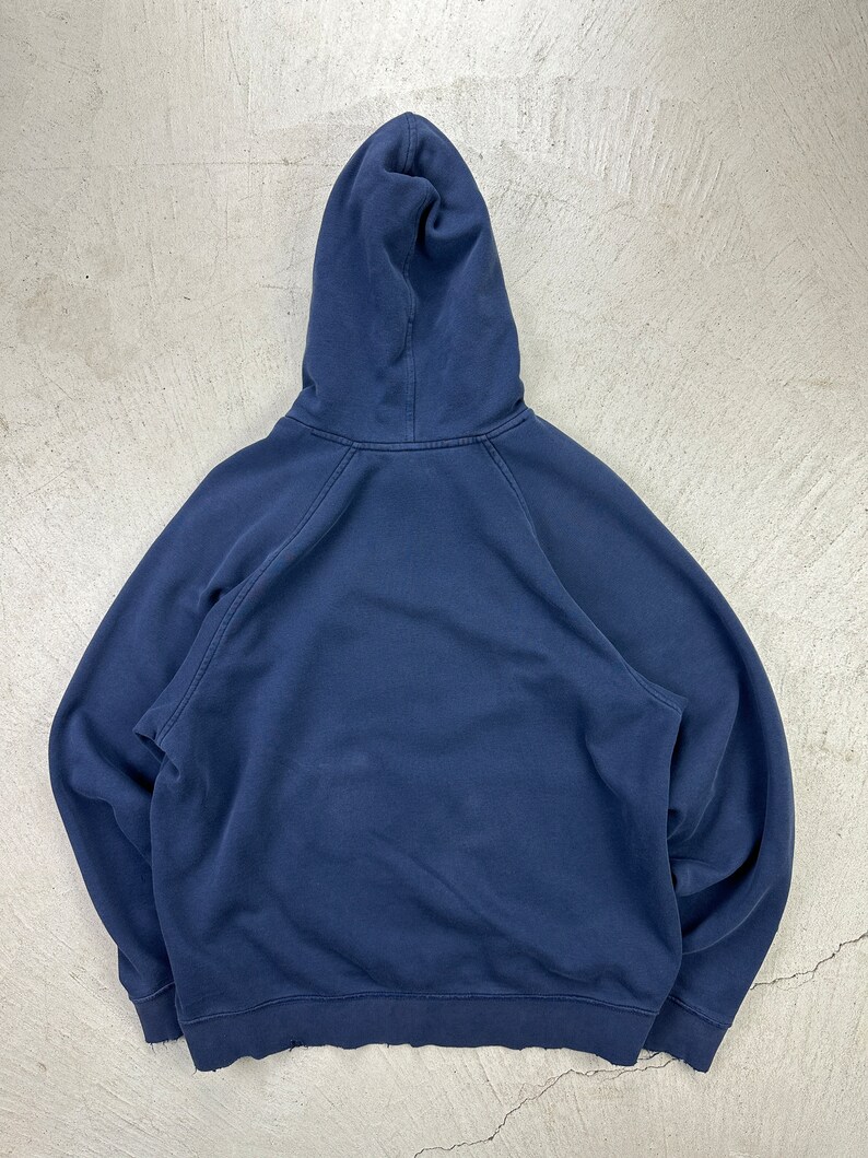 May include: A dark blue hooded sweatshirt with a drawstring hood. The sweatshirt has long sleeves and a kangaroo pocket.