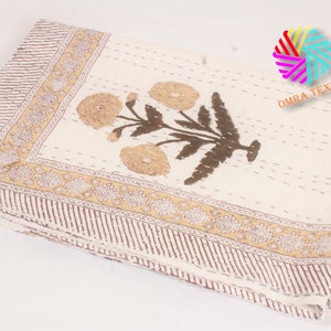 May include: Cream-colored textile with a floral design. The central motif features brown stems and tan flowers. A brown and tan border with a striped pattern and floral accents frames the edges. The textile is folded.