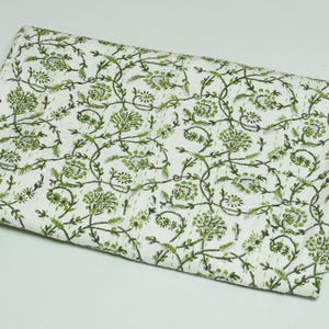 Green floral block print Kantha quilt rolled and unrolled on a white background, soft cotton hand-stitched blanket.