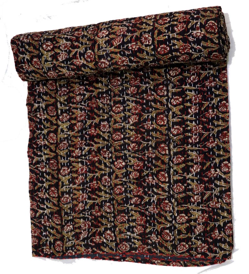 May include: A black kantha quilt with a floral pattern in shades of red, brown, and white. The quilt is rolled up and has a hand-stitched design.