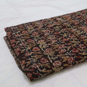 May include: Black cotton fabric with a floral pattern in shades of brown, red, and white. The fabric is quilted with a running stitch in white thread.