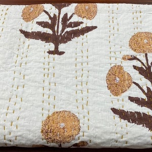 Può includere: Una trapunta in cotone bianco con un motivo ripetuto di steli e foglie marroni e fiori giallo oro testurizzati. Il tessuto è rifinito con file verticali di sottili impunture visibili realizzate con un filo giallo oro coordinato.
