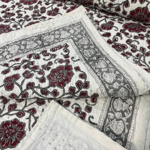 Puede incluir: Colcha de algodón blanco con un patrón floral en tonos burdeos y gris. La colcha está cosida a mano y tiene un diseño tradicional indio.