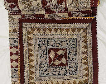 Puede incluir: Una colcha kantha de color marrón con un patrón geométrico en tonos marrones y beige. La colcha está cosida a mano con una puntada corrida y tiene un borde decorativo.
