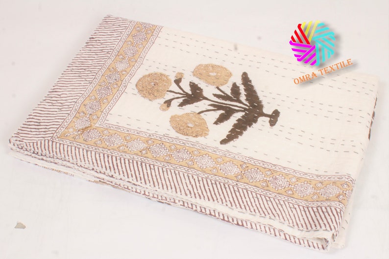 May include: Cream-colored textile with a floral design. The central motif features brown stems and tan flowers. A brown and tan border with a striped pattern and floral accents frames the edges. The textile is folded.