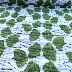May include: White fabric with a repeating pattern of green ginkgo leaves. The leaves are outlined in black and have a detailed vein pattern.