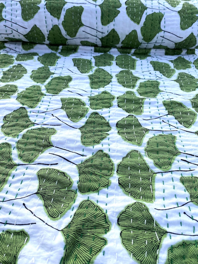 May include: White fabric with a repeating pattern of green ginkgo leaves. The leaves are outlined in black and have a detailed vein pattern.