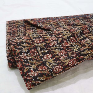 May include: A black cotton kantha quilt with a floral pattern in shades of brown, red, and white. The quilt is folded in half and has a hand-stitched design.