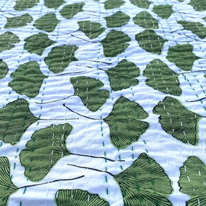May include: A white cotton kantha quilt with a green ginkgo leaf pattern. The quilt is hand-stitched and has a traditional Indian design.