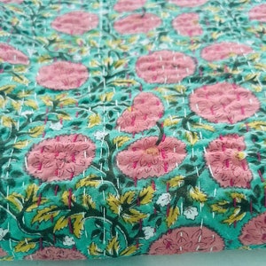 Könnte beinhalten: Eine türkisfarbene und rosafarbene Kantha-Steppdecke mit floralem Muster. Die Steppdecke ist aus Baumwolle und hat ein handgesticktes Design.