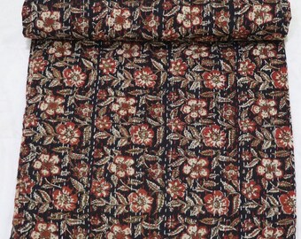 May include: A black kantha quilt with a floral pattern in shades of red, brown, and cream. The quilt is made of cotton and is hand-stitched.