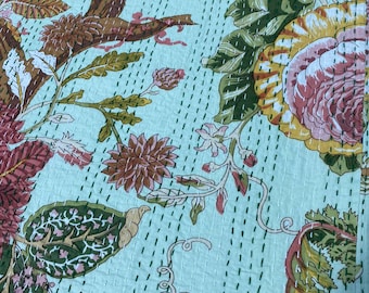 May include: A light blue floral quilt with a repeating pattern of large flowers and leaves in shades of pink, brown, green, and yellow. The quilt has a stitched texture.