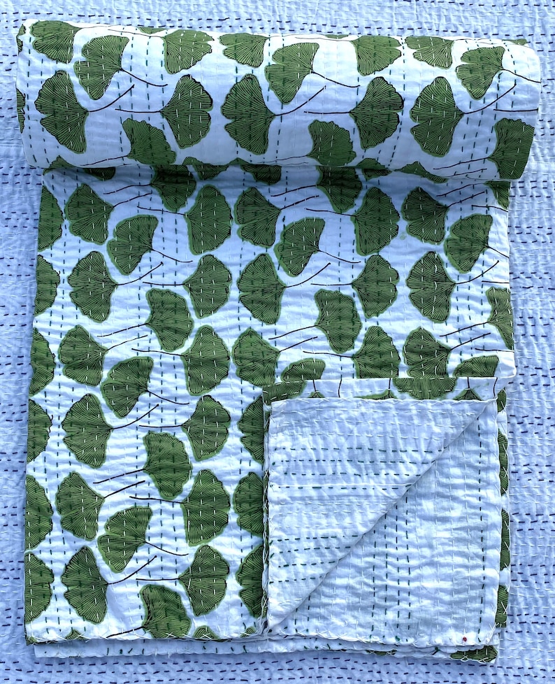 May include: A white kantha quilt with a green ginkgo leaf pattern. The quilt is folded in half and the pattern is visible on both sides.