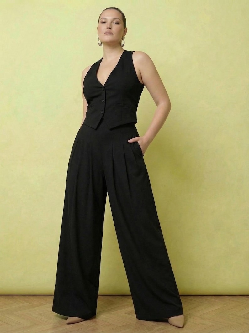 May include: A black vest and wide-leg pants set. The vest has a V-neck and button closure. The pants are high-waisted with pleats and pockets. The outfit is a solid black color, suitable for formal or business attire.