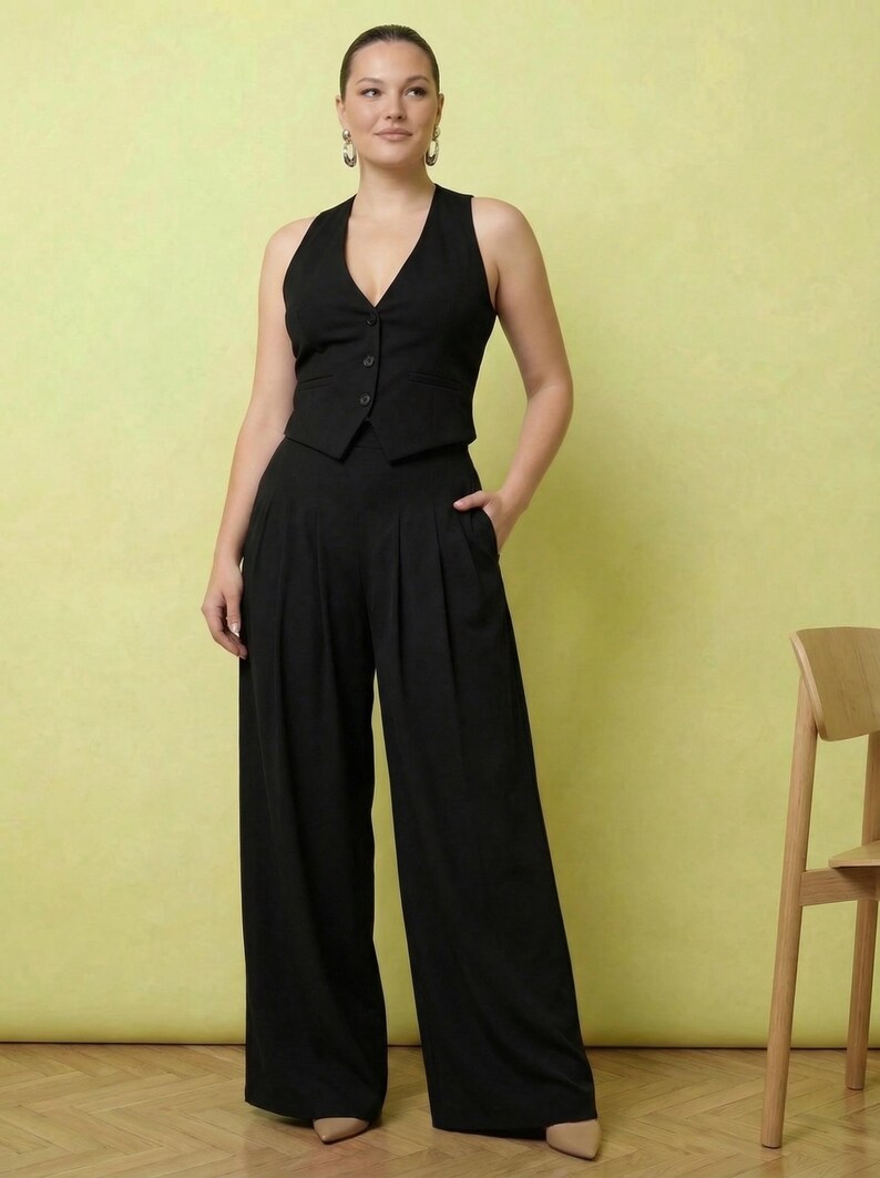 May include: A black sleeveless vest with a V-neckline and three front buttons paired with matching high-waisted wide-leg trousers featuring front pleats and side pockets. The ensemble is solid black and worn with pointed-toe beige heels.