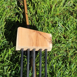 May include: A wooden arrow quiver with five black arrows attached to a wooden bow.