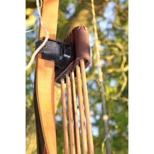 May include: A wooden bow with a brown leather quiver attached to it. The quiver holds several arrows.