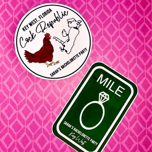 May include: Two stickers on a pink background. One is round with a rooster illustration and the text "Cock Republic" and "Sarah's Bachelorette Party". The other is a green rectangle with a diamond ring and the word "MILE".