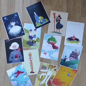 May include: A collection of 10 colorful illustrated prints featuring characters and scenes from popular animated films. The prints are arranged on a wooden surface.