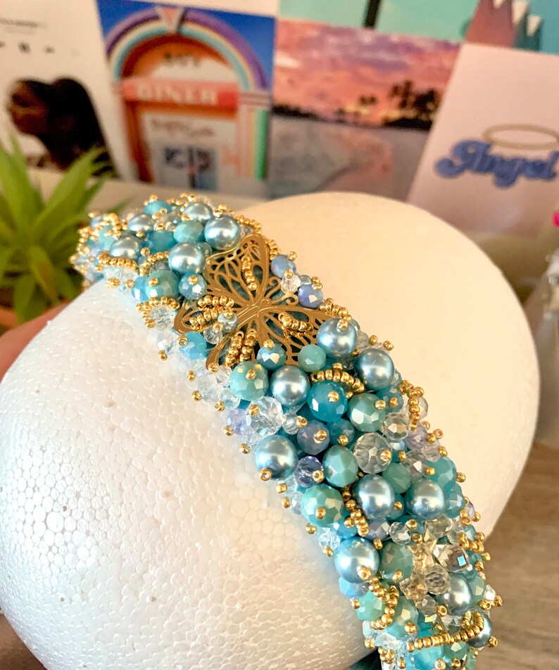 gold details,pearls and butterfly in the middle. Handmade embroidered headband luxe with genuine crystals of different shades of blue
