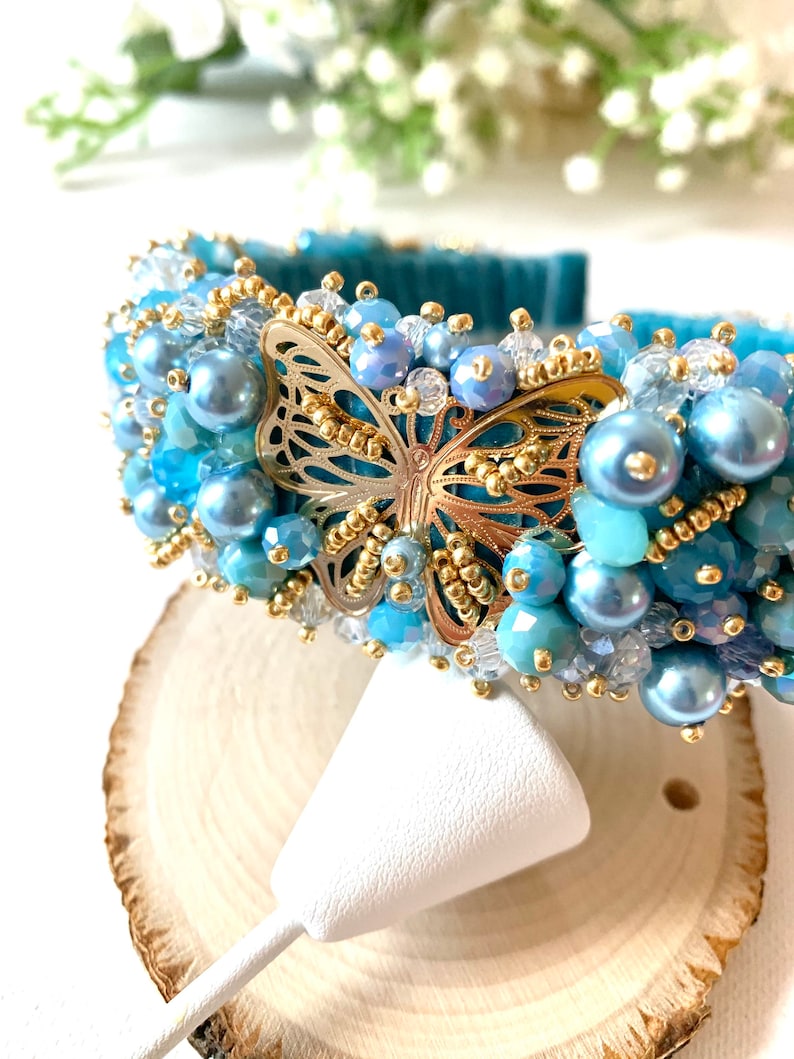 gold details,pearls and butterfly in the middle. Handmade embroidered headband luxe with genuine crystals of different shades of blue