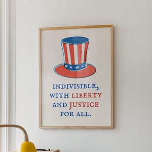 May include: A framed poster featuring a red, white and blue illustration of a top hat with stars. The text on the poster reads "INDIVISIBLE, WITH LIBERTY AND JUSTICE FOR ALL."