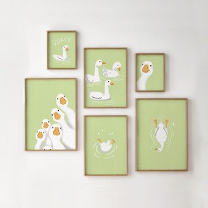 Puede incluir: Un conjunto de seis impresiones enmarcadas con ilustraciones de gansos sobre un fondo verde claro. Las impresiones est&aacute;n dispuestas en una cuadr&iacute;cula en una pared blanca. Una impresi&oacute;n presenta la palabra "QUACK" y un ganso nadando.