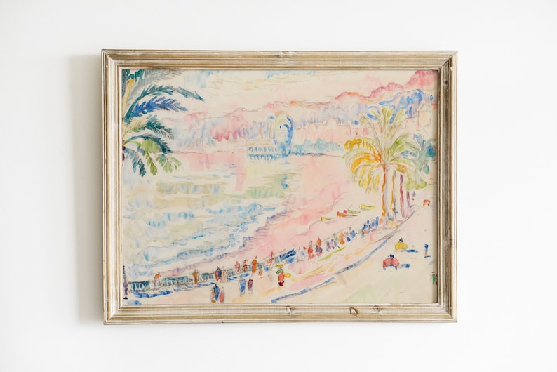 May include: Watercolor painting of a beach scene with palm trees, people, and buildings. The artwork features a pastel color palette with pink, blue, and yellow hues. The painting is framed in a gold-colored wooden frame.