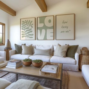 May include: A white sofa with green and beige cushions in a living room with three framed prints on the wall. The prints feature a green leafy design, the word "LOVE" in large green letters, and the text "how lucky are we".