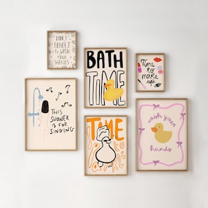 Op de afbeelding: Een verzameling ingelijste kunstprints met grillige illustraties en tekst. De prints bevatten zinnen als "Bath Time" en "Wash Your Hands", samen met afbeeldingen van een badeend en make-up. Het kleurenpalet omvat geel, roze en zwart.