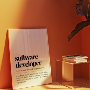 May include: A framed print with a white background and black text defining the word "software developer". The definition reads: "[sohf-t-wair dih-vel-uh-per] noun a caffeine fuelled wizard who turns coffee into code, fights bugs for a living, and makes stuff work - usually by saying, "It works on my machine."