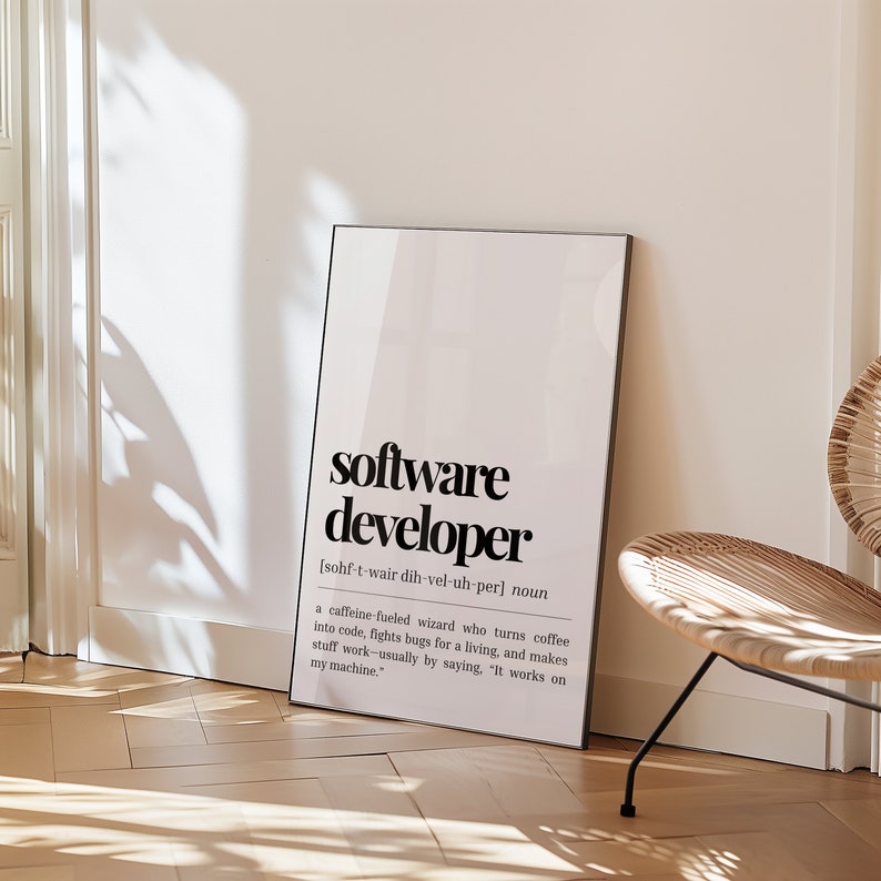 May include: A white framed poster with a black and white graphic design. The poster defines "software developer" as a "caffeine-fueled wizard who turns coffee into code, fights bugs for a living, and makes stuff work - usually by saying, "It works on my machine."