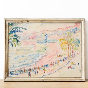 May include: A framed watercolor painting of a beach scene with palm trees, figures, and buildings. The artwork features pastel colors, including pink, blue, and yellow. The frame is a light, neutral color.