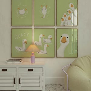 Puede incluir: Seis ilustraciones enmarcadas de gansos sobre un fondo verde claro. Las ilustraciones presentan gansos en varias poses, incluyendo nadar, volar y mirar al espectador. La palabra "QUACK" est&aacute; escrita en blanco en uno de los marcos.