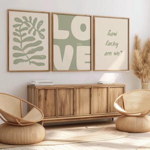 May include: Three framed prints with a green background. The left print features a green leaf design. The middle print has the word "LOVE" in large white letters with the word "YOU" in smaller letters below. The right print has the text "how lucky are we" in white lettering.