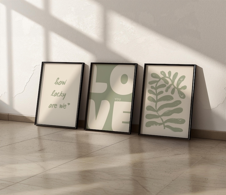 May include: Three framed prints with a minimalist design. The first print has the text "how lucky are we." The second print has the word "LOVE" in large, green letters with the word "YOU" in smaller letters below. The third print has a green abstract leaf design.
