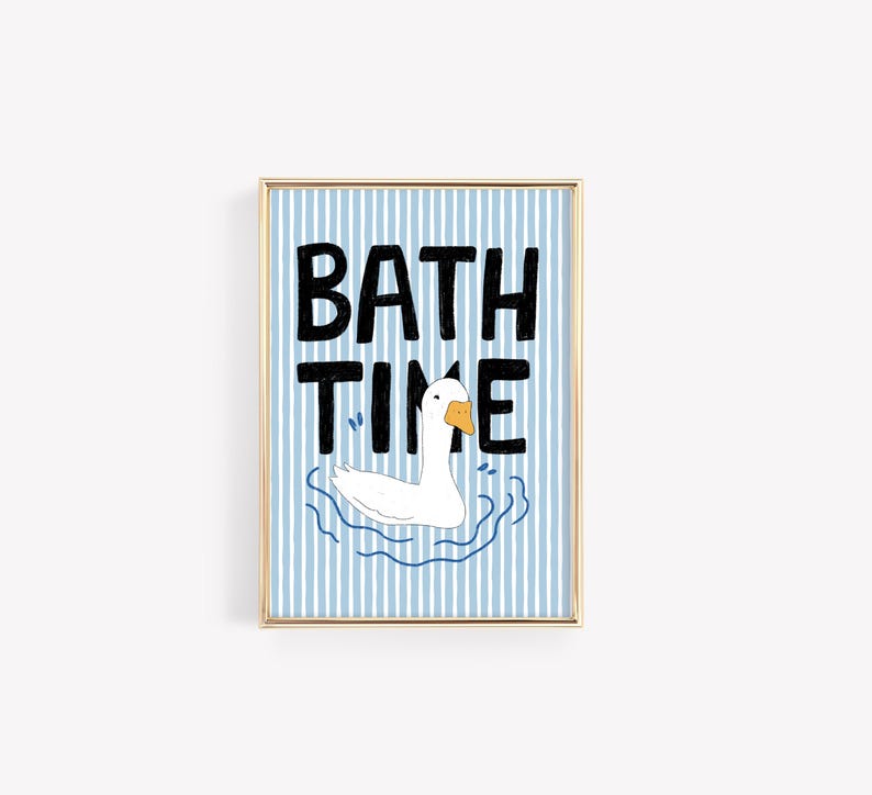 May include: A framed wall art print featuring a white goose with an orange beak swimming in blue water. The background consists of vertical light blue and white stripes. The black hand-drawn text BATH TIME is centered above the goose illustration.