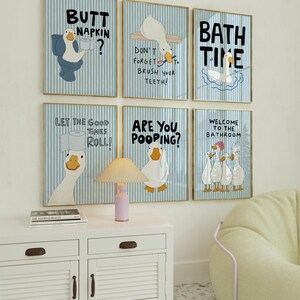 May include: Six framed wall art prints featuring cartoon ducks on a light blue and white striped background. The prints include text such as Butt Napkin, Don't Forget To Brush Your Teeth, Bath Time, Let The Good Times Roll, Are You Pooping, and Welcome To The Bathroom.