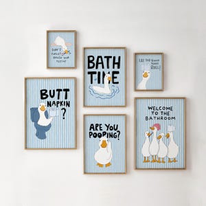 May include: A set of six framed wall art prints featuring white ducks on a light blue and white vertical striped background. The prints include humorous text such as "Bath Time," "Butt Napkin?," "Are You Pooping?," and "Welcome to the Bathroom."