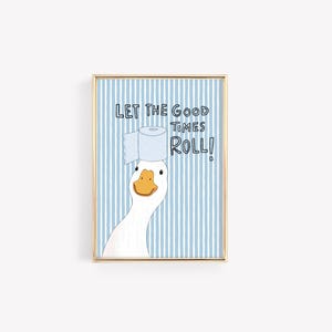 May include: A framed wall art print featuring a white goose with an orange beak balancing a roll of toilet paper on its head. The background consists of vertical light blue and white stripes with the text LET THE GOOD TIMES ROLL! in black.