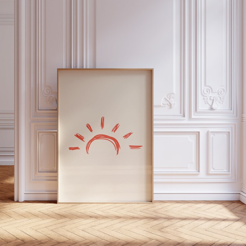 May include: A framed print with a simple, hand-drawn illustration of a sun in a coral color on a cream background.