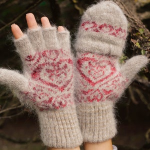 May include: A pair of light grey knitted gloves featuring a red heart design. The gloves have a fingerless design with a mitten cover. The gloves are made of a soft, fuzzy material. The mittens are perfect for keeping hands warm.