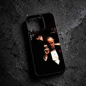 Könnte beinhalten: Schwarze Handyhülle mit einer Szene aus dem Film "Der Pate". Das Bild zeigt einen Mann im Smoking, der eine Zigarette hält. Die Hülle hat einen schwarzen Rand und einen Ausschnitt für die Kamera.