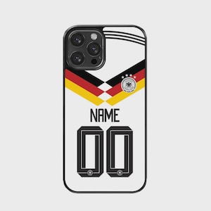 Könnte beinhalten: Eine weiße Smartphone-Hülle mit einem Grafikdesign, das an das Trikot der deutschen Fußballnationalmannschaft erinnert. Das Design zeigt schwarze, rote und goldene Chevron-Streifen, das deutsche Adlerwappen, das Wort NAME und die Zahl 00 in Schwarz.