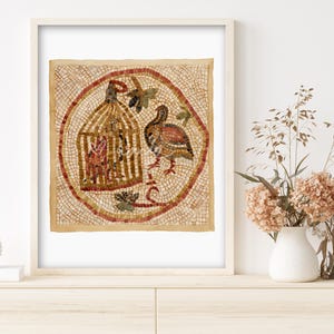 May include: Framed mosaic art featuring a bird and a cage within a circular design. The artwork uses a palette of warm earth tones, including reds, browns, and tans. The mosaic is set against a light beige background, and the frame is white.