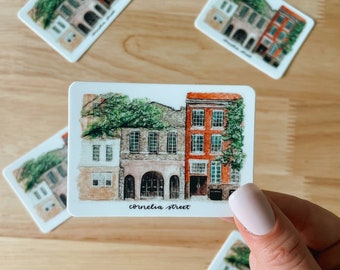 May include: A set of four watercolor illustrations of historic buildings in Charleston, South Carolina. Each illustration features a different building with a unique architectural style and is labeled with the street name. The illustrations are printed on white cardstock and are perfect for adding a touch of Southern charm to any space.
