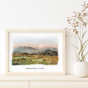 May include: A watercolor painting of a mountain range with a sunset sky. The text "Appalachian Trail" is written in cursive at the bottom of the painting.
