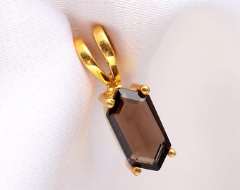 May include: A gold pendant with a brown gemstone. The gemstone is cut in a rectangular shape with beveled edges.