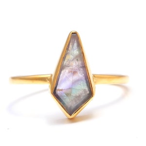 May include: A gold ring with a large, faceted, iridescent purple gemstone in a geometric setting.