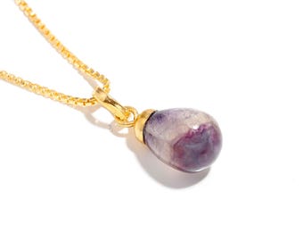May include: A gold chain necklace with a purple and white teardrop-shaped pendant.